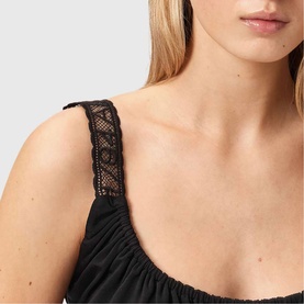 Model wearing All Saints Celena Logo Strap Top in black, close-up showing lace logo-embroidered straps and scoop neckline detail.