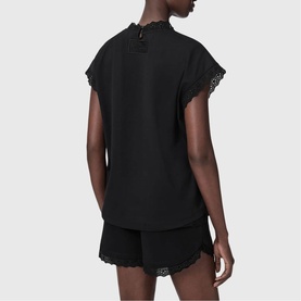 Model wearing All Saints Lele Lace Trim Top in black with lace-trimmed sleeves and back split, styled with matching black lace-trim shorts.