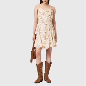 Model wearing All Saints Claire Floral Mini Flared Dress in caramel off-white with cowl neck and double straps, styled with tan cowboy boots and