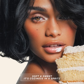 Model with Gisou Honey Infused Vanilla Glaze Hair Perfume, glossy lips and styled black bob, holding a slice of vanilla cake
