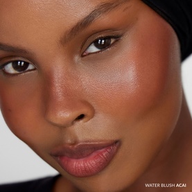 Model wearing No Brand UDA Water Blush in Apricot, shown as a natural flush on cheeks with a radiant, skin-like finish