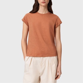 Model wearing All Saints Anna Back Logo T-Shirt in Pecan Brown with turn-back cuffs and crew neck, styled with cream wide-leg trousers.