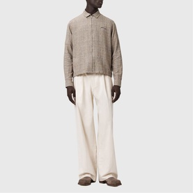 Model wearing All Saints Keal Check Jacket in sediment brown with zip fastening, styled with cream wide-leg trousers.