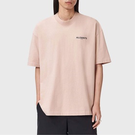 Model wearing All Saints Hallis Oversized Graphic Logo T-Shirt in Sunbaked Pink with small front logo print, styled with black trousers.