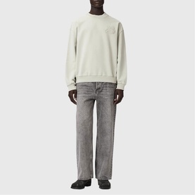 Model wearing a light grey crew neck sweatshirt with subtle logo detail, styled with grey straight-leg jeans