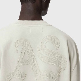 Model wearing cream sweatshirt with large tonal embossed letter appliqu&eacute; detail across the back, close-up rear view