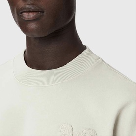Model wearing All Saints Insignia Logo Sweatshirt in Sea Green with tonal gothic logo appliqu&eacute; detail at chest, crew neckline visible.