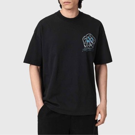 Model wearing black oversized crew neck T-shirt with small blue and grey graphic chest logo print, paired with black joggers.