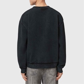 Model wearing All Saints Dash Logo Sweatshirt in Washed Black, back view, crew neck with distressed finish, styled with grey jeans.