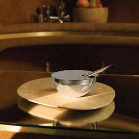 Alessi Diffuser Set in Basalt, polished stainless steel canister with spoon rest on a gold marble-effect stand, warm ambient setting
