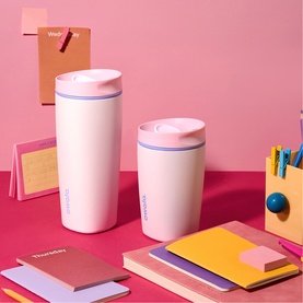 Owala SmoothSip Slider Travel Mug in Candy Coated pink, two sizes shown styled with notebooks and stationery on a pink desk
