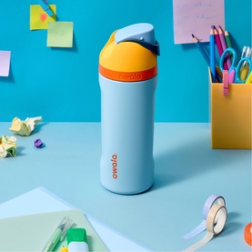 Owala FreeSip&reg; Water Bottle Day Dreams 16oz in light blue with yellow and navy lid, on a blue desk styled with stationery and sticky notes