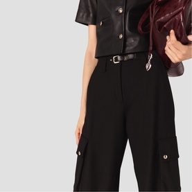 Model wearing Maje black wide-leg cargo trousers with gold-tone buttons, styled with black leather crop top and red bag.