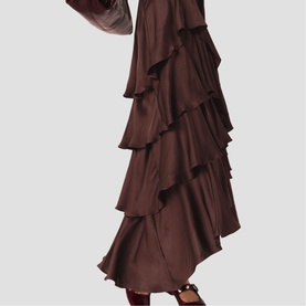 Model wearing a chocolate brown tiered ruffle maxi skirt with long sleeves, flowing asymmetric hem