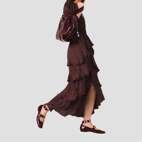 Model carrying a dark burgundy shoulder bag with chain detail, styled with a tiered ruffle maxi dress and studded ballet flats.