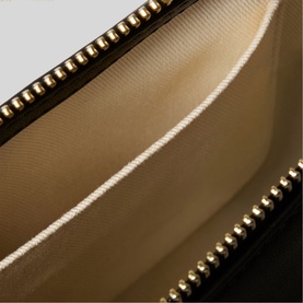 Claude Pierlot black wallet interior view showing beige lining and gold-tone stud trim detail along edges.
