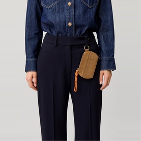 Model wearing Claude Pierlot Disc Dump in clear tan, clipped to navy tailored trousers, styled with a dark denim jacket.