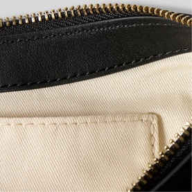 Claude Pierlot black wallet interior showing cream fabric lining and card slot with gold-tone zip closure visible at top.