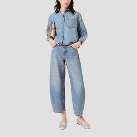 Model wearing Maje light blue denim shirt and wide-leg barrel jeans, styled with a tan bag and white printed ballet flats