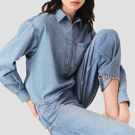 Model wearing Maje light blue denim popover shirt with chest pocket, styled with matching wide-leg denim jeans