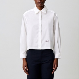 Model wearing Claude Pierlot white cropped shirt with point collar, long sleeves and small logo detail, styled with navy trousers.