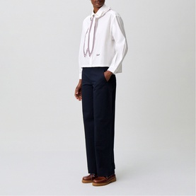 Model wearing Claude Pierlot white hoodie with drawstring detail, styled with navy wide-leg trousers and tan loafers.
