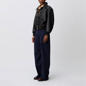 Model wearing Claude Pierlot black lambskin Leather Bomber Jacket with gold-tone press studs and patch pockets, styled with navy wide-leg trousers.