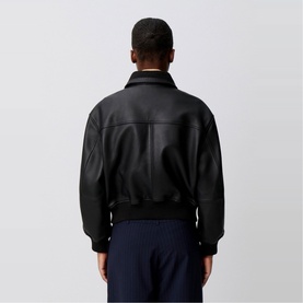 Model wearing Claude Pierlot Leather Bomber Jacket in black lambskin, rear view, with navy trousers visible below