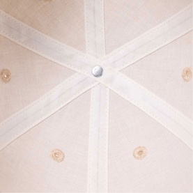 Maje clear cap close-up showing crown panel construction with silver metal button detail and embellished fabric panels
