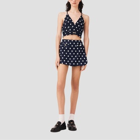 Model wearing Maje navy dots print crop top and mini skirt co-ord set, styled with white socks and black loafers