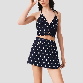 Model wearing Maje Womens French Dress in navy dots print, styled as a two-piece with matching wrap crop top and mini skirt