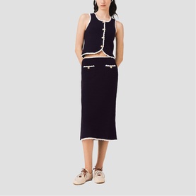 Model wearing Maje Womens French Dress in navy and white contrast trim knit crop top and midi skirt co-ord set, styled with beige loafers