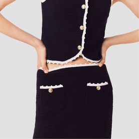 Model wearing Maje Womens French Dress in black and white knit, featuring gold button detail, scallop trim, and cropped top with matching skirt