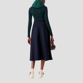 Model wearing Maje Womens French Dress in navy midi skirt with green turtleneck, carrying small burgundy bag, styled with cream loafers
