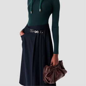 Model wearing Maje Womens French Dress in dark green and navy, styled with a black belted waist and carrying a burgundy leather bag.