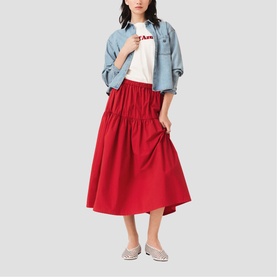 Model wearing Maje Womens French Dress in red, full midi silhouette with gathered waist, styled with denim jacket and white tee