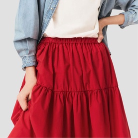 Model wearing Maje gold tiered midi skirt with elasticated waist, styled with white top and denim jacket