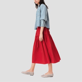 Model wearing Maje Womens French Dress in red full midi skirt with gathered waist, styled with light blue denim shirt and checked flats