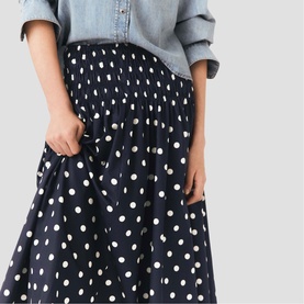 Model wearing Maje navy dots print midi skirt with gathered waist, styled with a light blue denim shirt