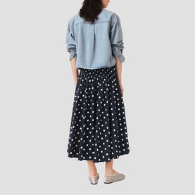 Model wearing Maje Womens French Dress in navy dots print, shown from behind, styled with a light blue shirt and checked flats.