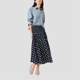 Model wearing Maje navy dots print midi skirt with light blue denim shirt and white mesh ballet flats.