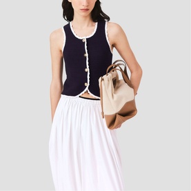 Model wearing Maje navy ribbed button-front tank top with white trim, styled with white midi skirt and carrying a beige tote bag