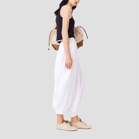 Model carrying Maje multi-tone backpack, styled with navy tank top, white maxi skirt and beige lace-up trainers