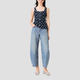 Model wearing Maje navy dots print top with square neckline, styled with light wash barrel-leg jeans and silver flat shoes