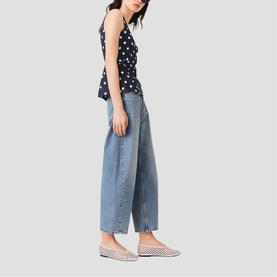 Model wearing Maje navy dots print top, styled with wide-leg light blue cropped jeans and checked flat shoes.