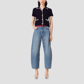 Model wearing Maje navy short-sleeve knit top with white trim, styled with light blue wide-leg jeans, red belt, and silver heels.