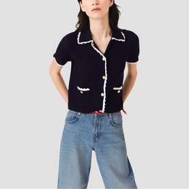 Model wearing Maje navy blue knit short-sleeve cardigan with white contrast trim and pearl buttons, styled with light blue wide-leg jeans