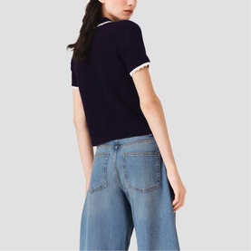 Model wearing Maje navy short-sleeve knit top with white trim detail, styled with wide-leg light blue jeans, rear view.