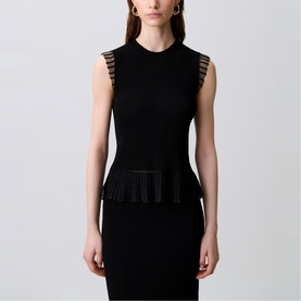 Model wearing Claude Pierlot Rib Knit Top in black, sleeveless with sheer ruffle armholes and flared sheer knit lower section with opaque hem trim.