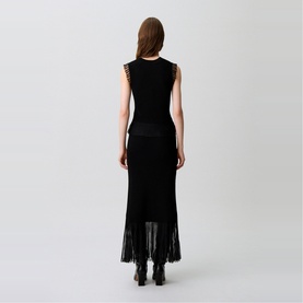 Model wearing Claude Pierlot Rib Knit Top in black, sleeveless with sheer ruffle armholes and flared fringed hem, styled with black maxi skirt and